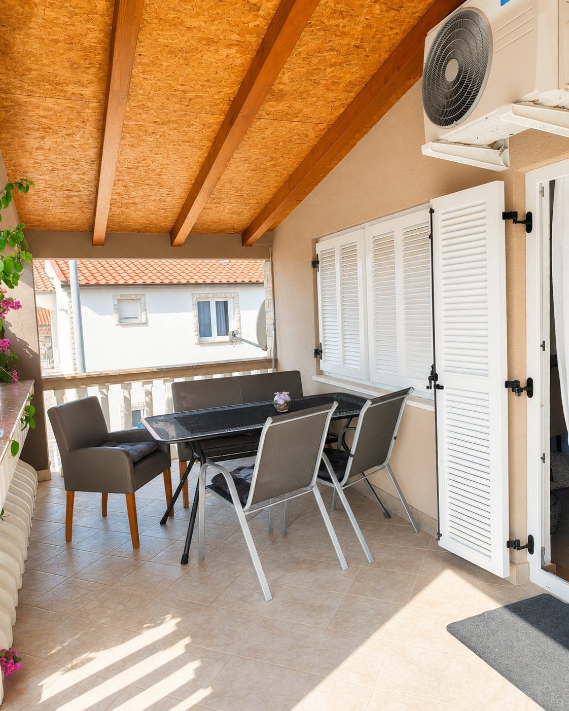 The covered balcony with a dining table for four, seen from the apartment door