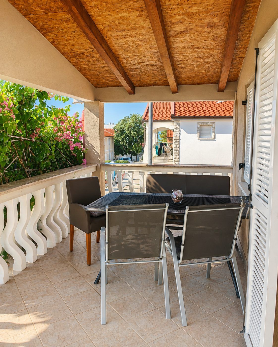 The covered balcony with dining table and bougainvillea