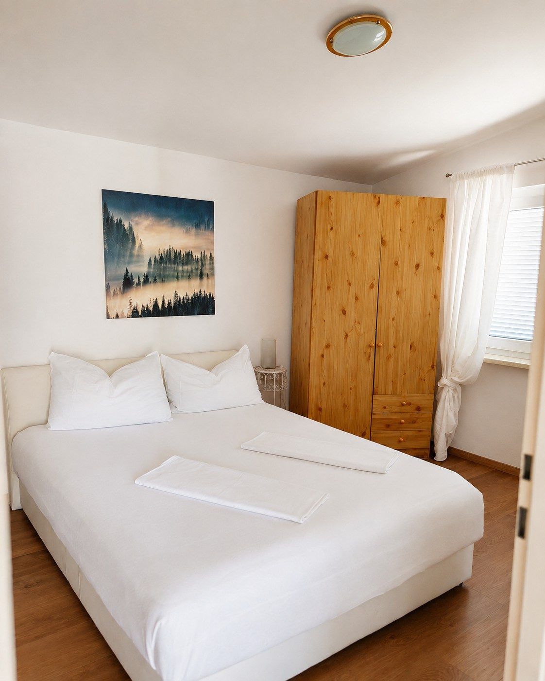 Bedroom with double bed and pine wardrobe