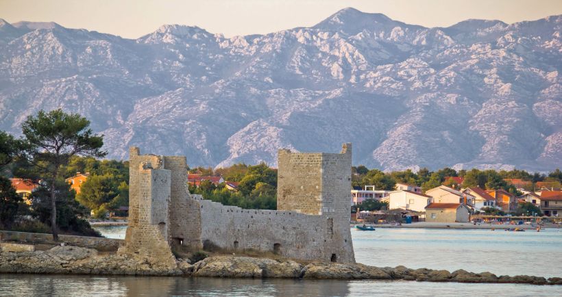 The Kaštelina fortress on the water, with the village and the Velebit mountains behind it