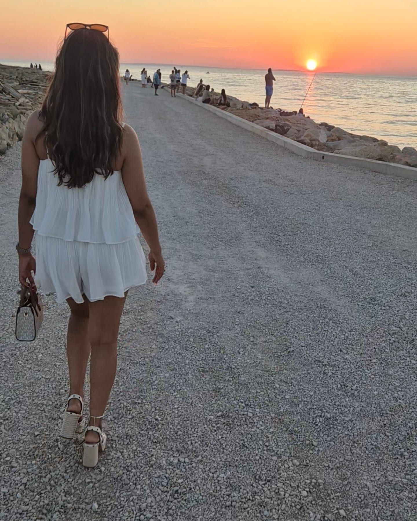 An evening walk on the gravel path by the sea on Vir, the sun setting over the water